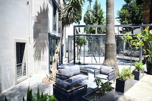 An outdoor seating area with modern furniture, surrounded by glass walls and potted plants. - MyElla Marina Hotel (Bodrum)