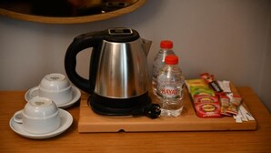 A kitchen area with a kettle, two cups, a bottle of water, and some food items on a wooden board. - MyElla Marina Hotel (Bodrum)