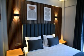 A hotel room with a large bed, two bedside tables, and a wooden panel wall with artwork. - MyElla Marina Hotel (Bodrum)