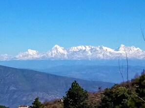 A mountain range with snow-capped peaks under a clear sky. - A Boutique Himalayan retreat where nature, serenity & luxury awaken your soul. (Hartola)