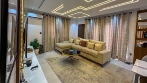 A modern living room with a sofa, a coffee table, and curtains. - 2-Bedroom Luxury Apartment | Fast Wi-Fi | Smart TV | 24/7 Power & Security (Lagos)