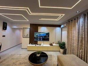 A modern living room with a flat-screen TV, a round coffee table, and a sofa. - 2-Bedroom Luxury Apartment | Fast Wi-Fi | Smart TV | 24/7 Power & Security (Lagos)
