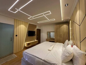 Une chambre moderne avec un lit, un téléviseur à écran plat, une armoire en bois et un miroir.