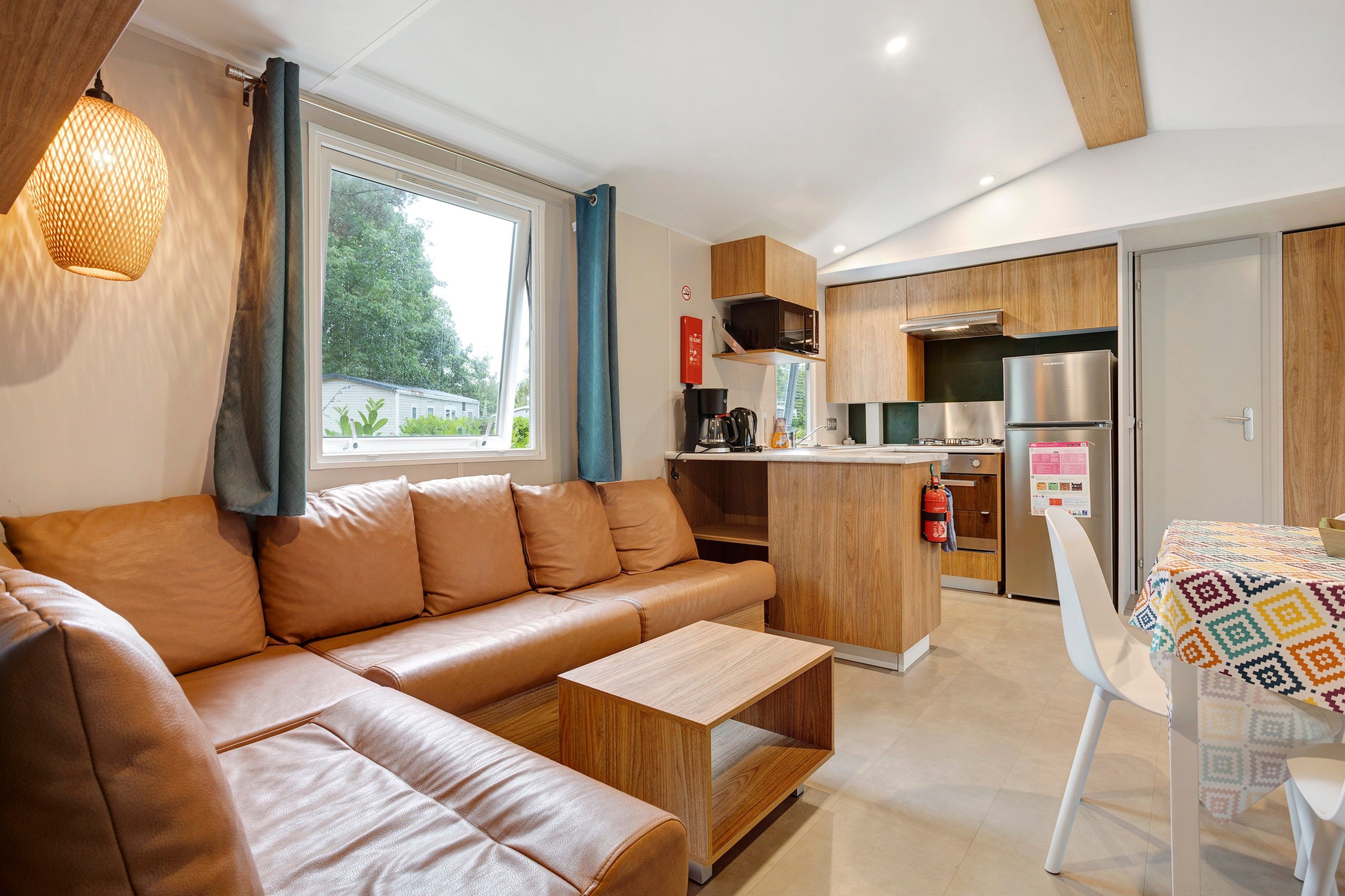 Een moderne woonkamer met een bank, een klein tafeltje en een eethoek met een tafelkleed met patroon.
