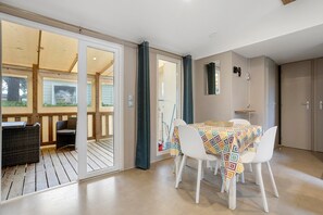 Een kamer met een eettafel, stoelen en uitzicht door een glazen deur op een terras.
