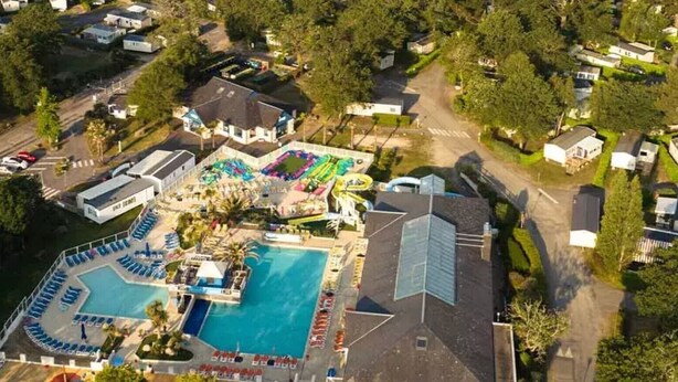 An aerial view of a resort with multiple swimming pools, a large central pool, and a variety of buildings and structures. - Mobile Home “On Domaine Kerlann” with Shared Pools and Private Terrace (Pont-Aven)