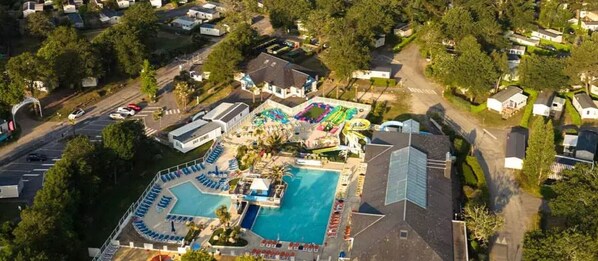 An aerial view of a resort with multiple swimming pools, a large central pool, and a variety of buildings and structures. - Mobile Home “On Domaine Kerlann” with Shared Pools and Private Terrace (Pont-Aven)
