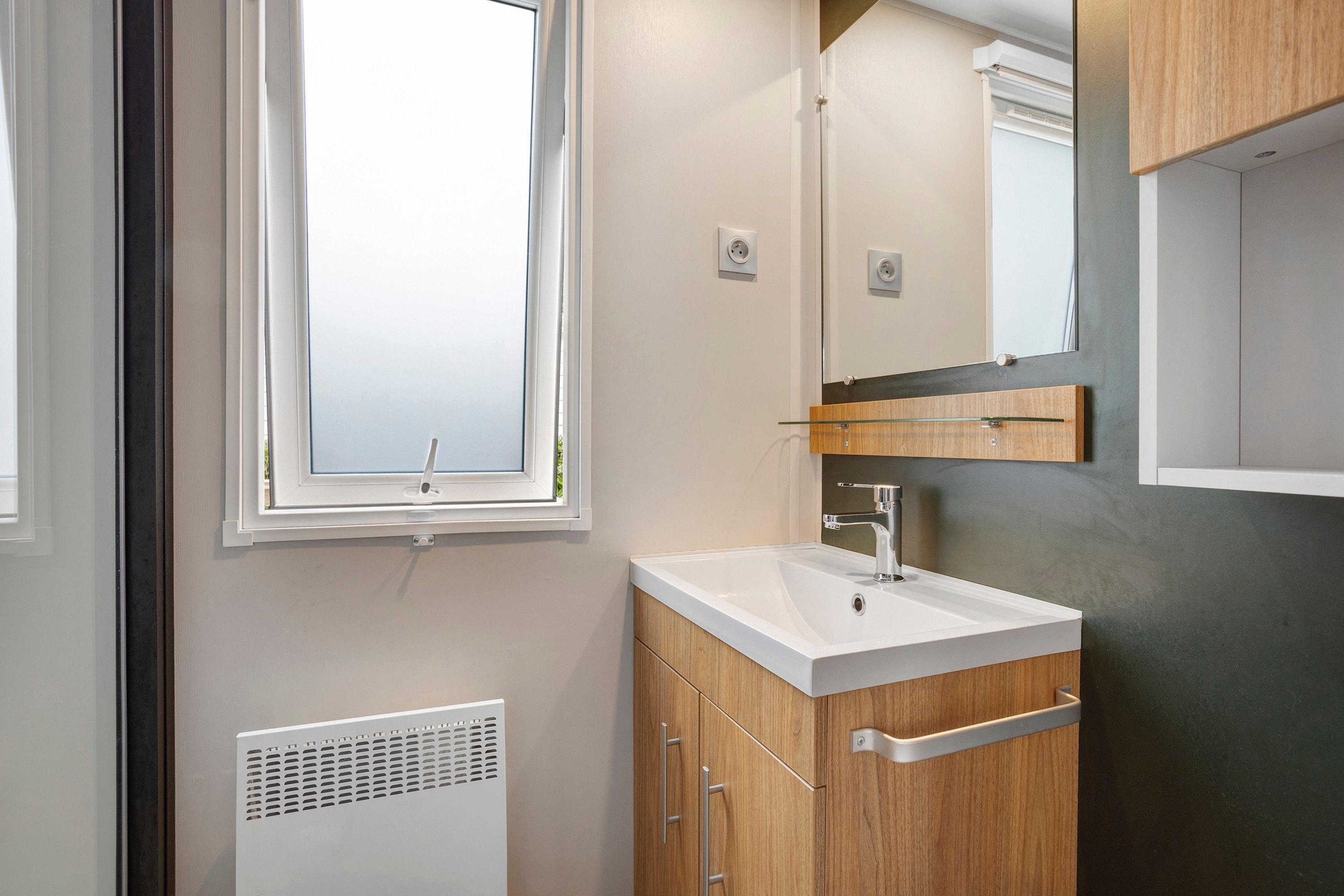 Une salle de bain moderne avec une fenêtre, un lavabo et un miroir.