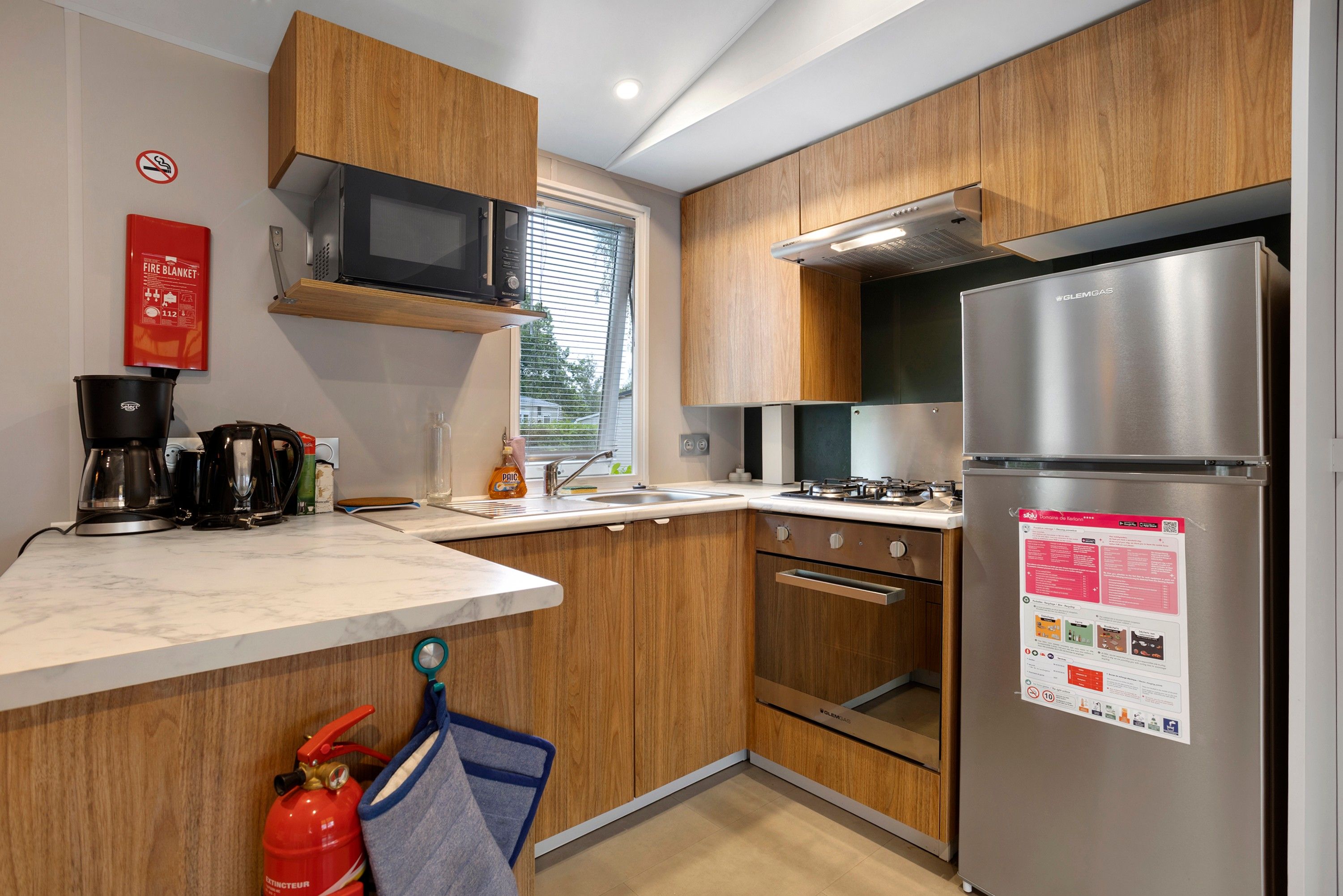 Una cocina moderna con armarios de madera, un refrigerador de acero inoxidable, un microondas y una estufa a gas.