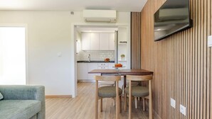 A modern kitchen with white cabinets, a dining table with chairs, and a flat-screen TV mounted on the wall. - Olival Dream House - Boutique House w/ Pool (Pedorido)