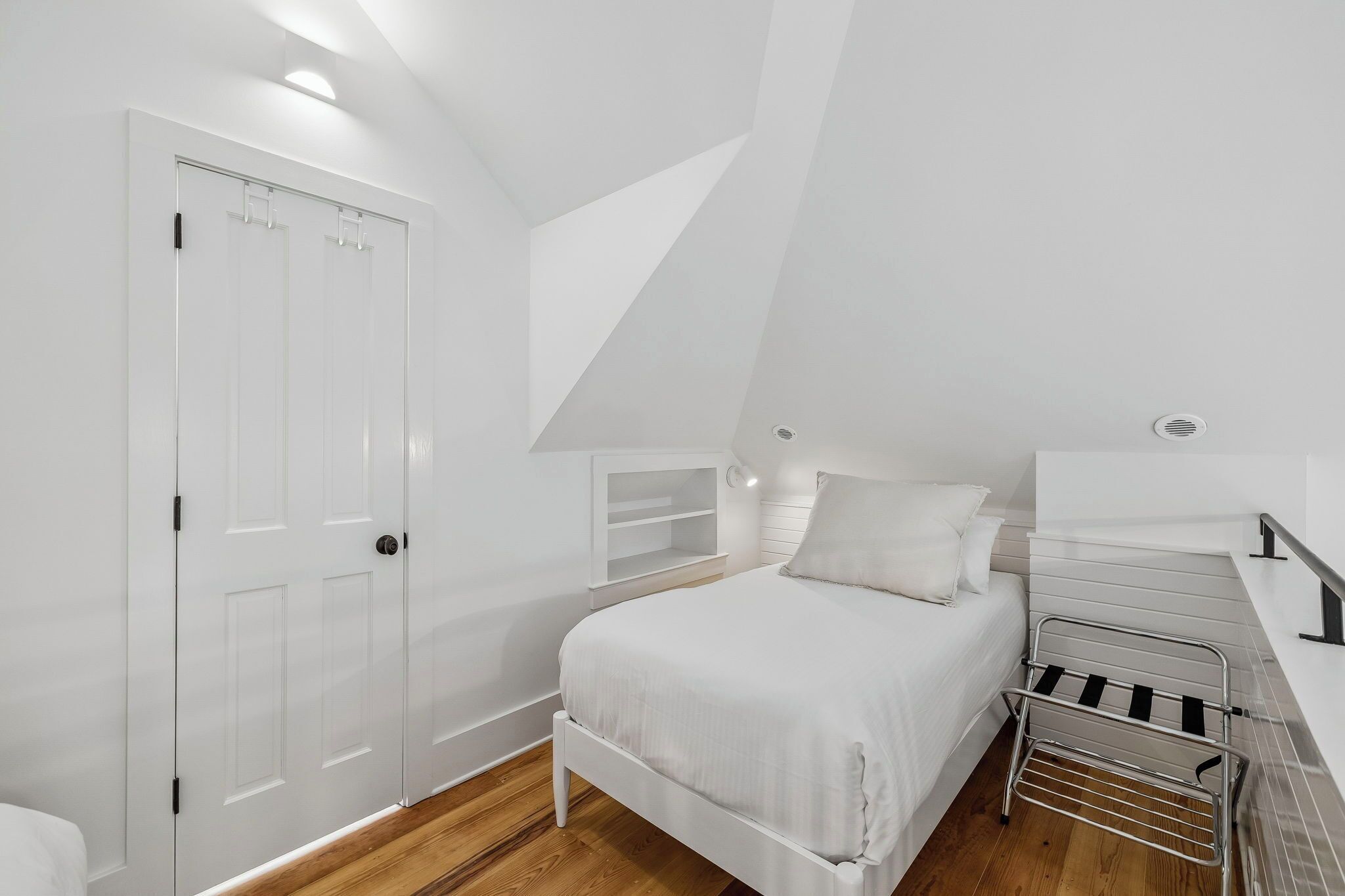 A bedroom with a bed, a wardrobe, a shelf unit, and a radiator.