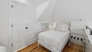 A bedroom with a bed, a wardrobe, a shelf unit, and a radiator.