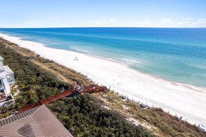 Une plage avec une promenade en bois menant à une zone aménagée avec une terrasse.