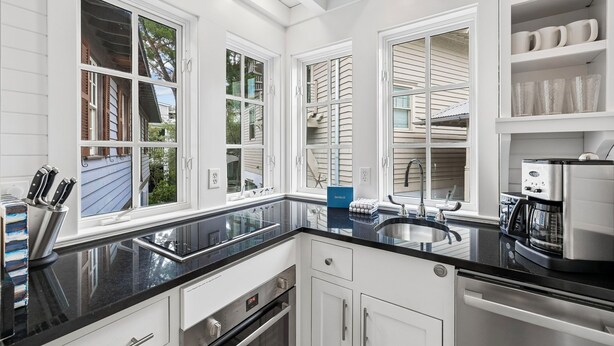 A modern kitchen with a black countertop, stainless steel appliances, and white cabinetry.