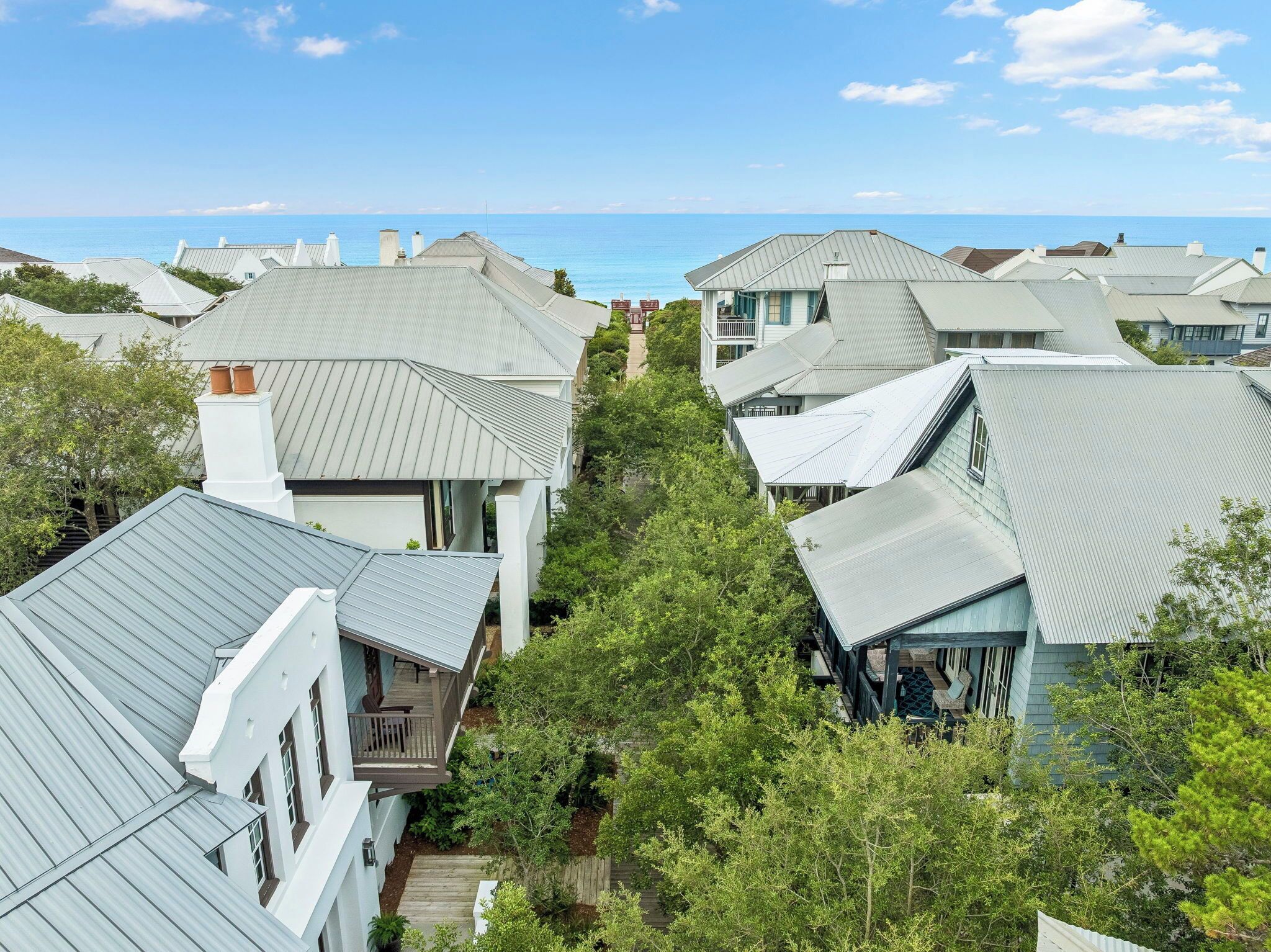 A residential area with houses featuring gabled roofs and a clear view of the ocean.