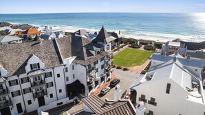 A coastal building with multiple stories, a visible lawn, and a view of the ocean.