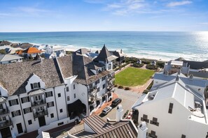 A coastal building with multiple stories, a visible lawn, and a view of the ocean.