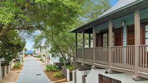 A pathway leading to a building with a porch and a covered area.