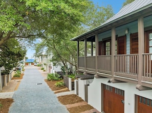 A pathway leading to a building with a porch and a covered area.