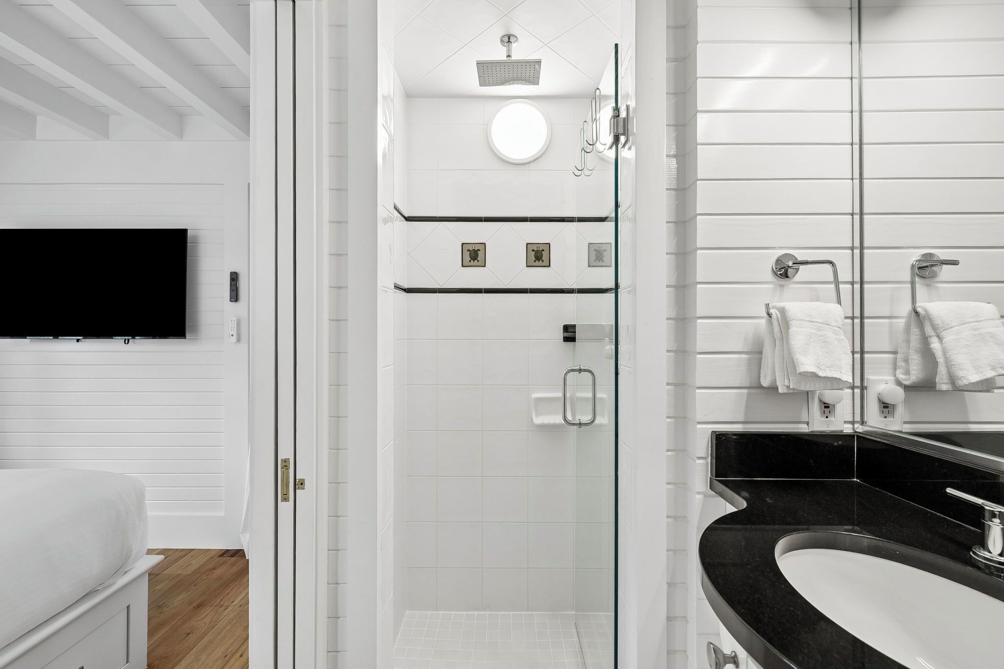 A modern bathroom with a glass-enclosed shower, a black sink, and a white toilet.