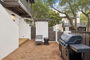 Une terrasse avec un barbecue, une chaise et une table.