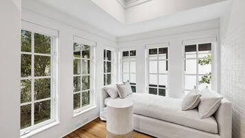A room with a white sofa, a round side table, and large windows with white frames.