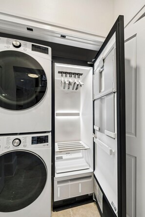 Une petite buanderie équipée d’un lave-linge, d’un sèche-linge et d’un réfrigérateur intégré doté d’un compartiment congélateur.