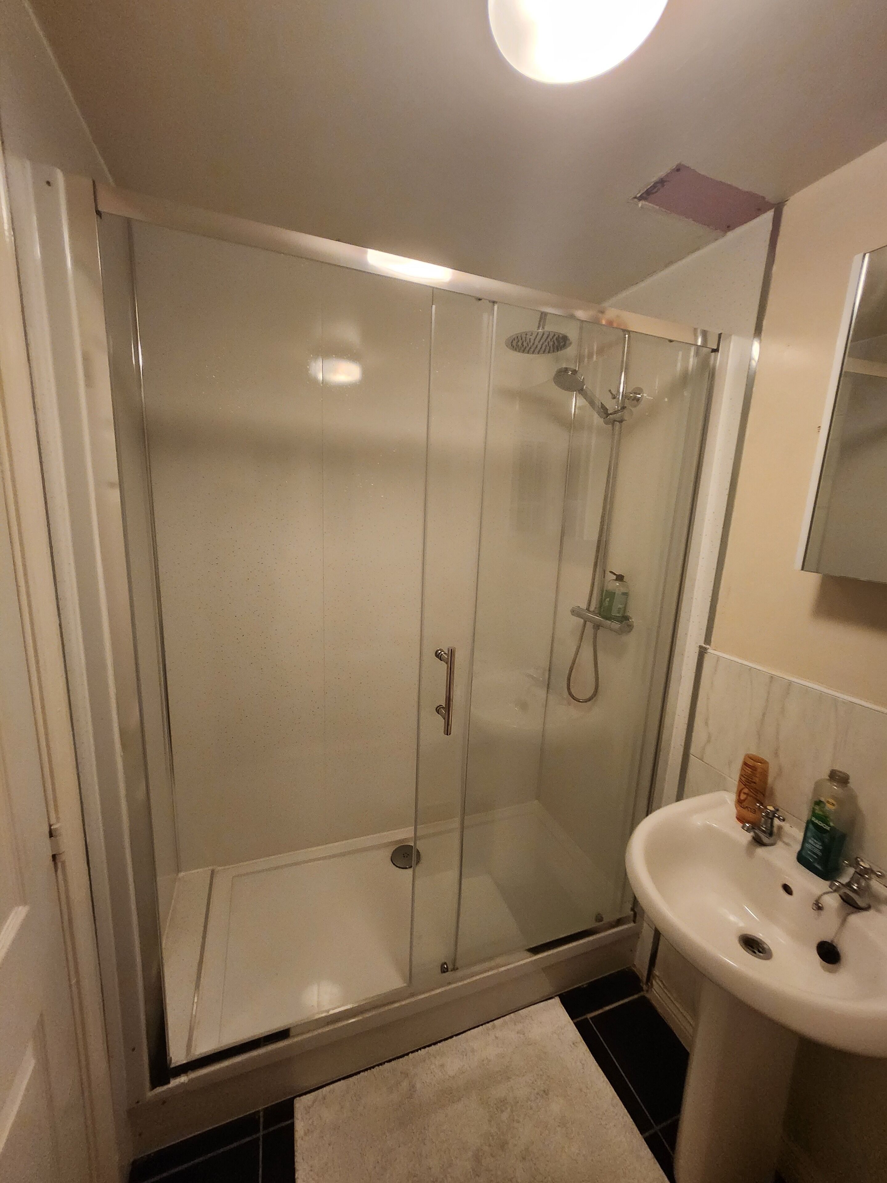 A bathroom with a glass-enclosed shower, a white sink, and a mirror above the sink.