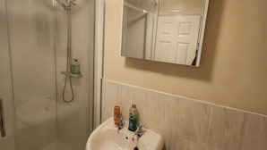 Et badeværelse med bruseniche, et håndvaskstel og et toilet.