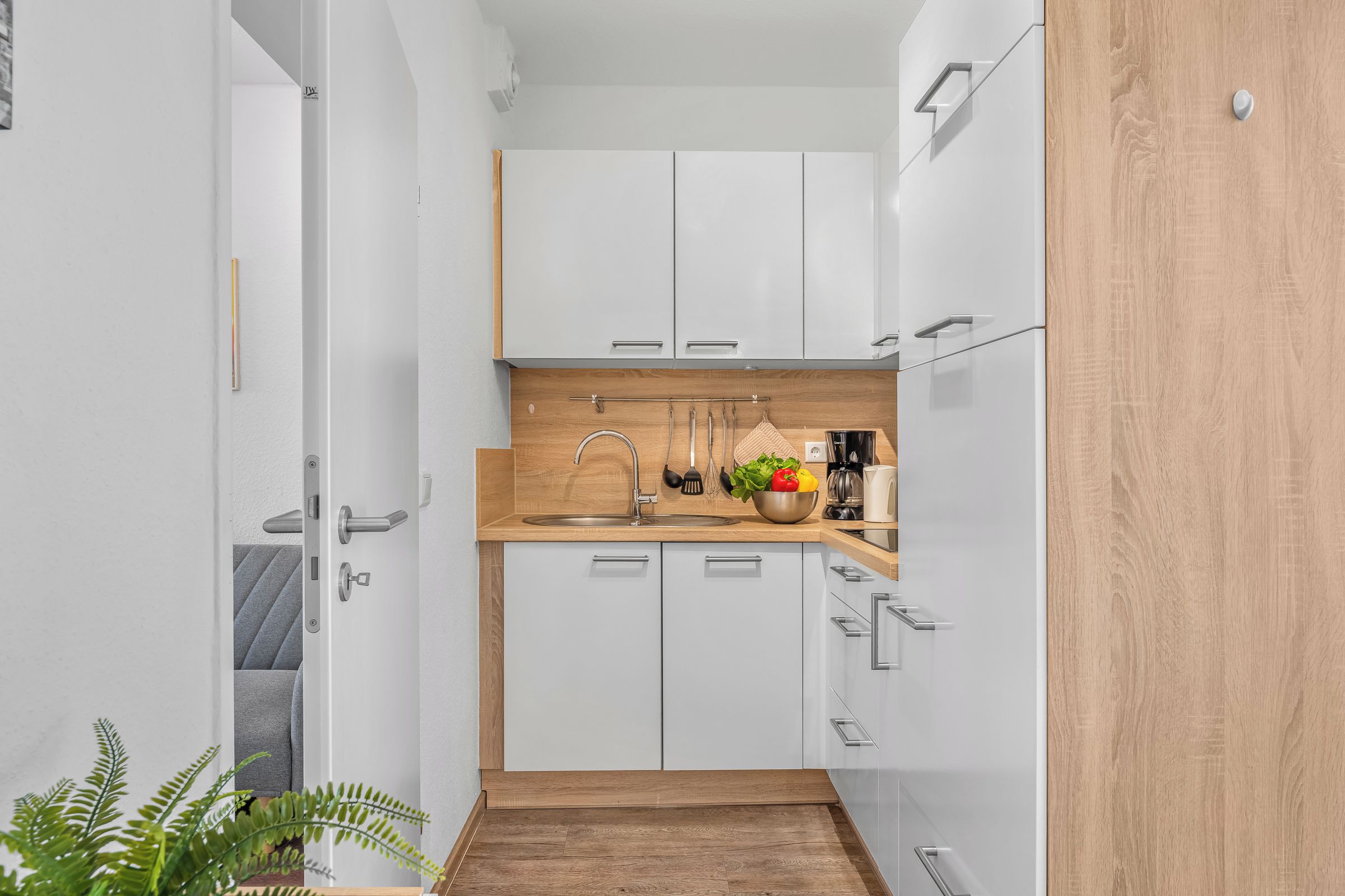 Eine schmale Küche mit weißen Schränken, einer Holz Arbeitsplatte und einem Spülbecken.