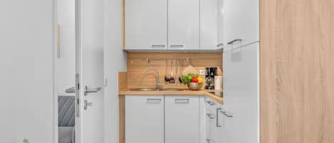 Una cocina estrecha con armarios blancos, una encimera de madera y un fregadero.