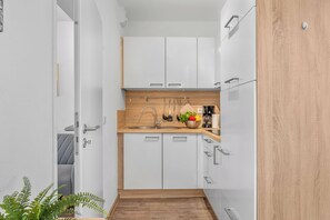 Eine schmale Küche mit weißen Schränken, einer Holz Arbeitsplatte und einem Spülbecken.