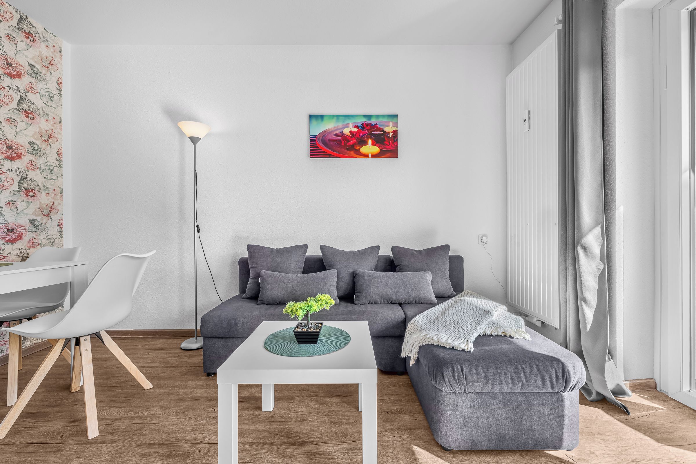 Un salon moderne avec un canapé gris, une table basse blanche et une petite plante en pot.