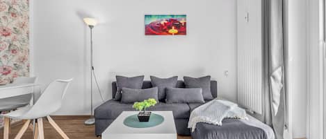 Un salon moderne avec un canapé gris, une table basse blanche et une petite plante en pot.