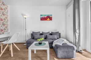 A modern living room with a grey sofa, white coffee table, and a small potted plant. - Cozy Ground-Floor Apartment "Malo" in Büsum – Perfect for Your North Sea Vacation (Büsum)