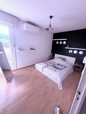 A bedroom with a bed, a ceiling fan, a window, and a door. - Large family home with spacious, landscaped terraces, 100 meters from the beach (Mauguio)