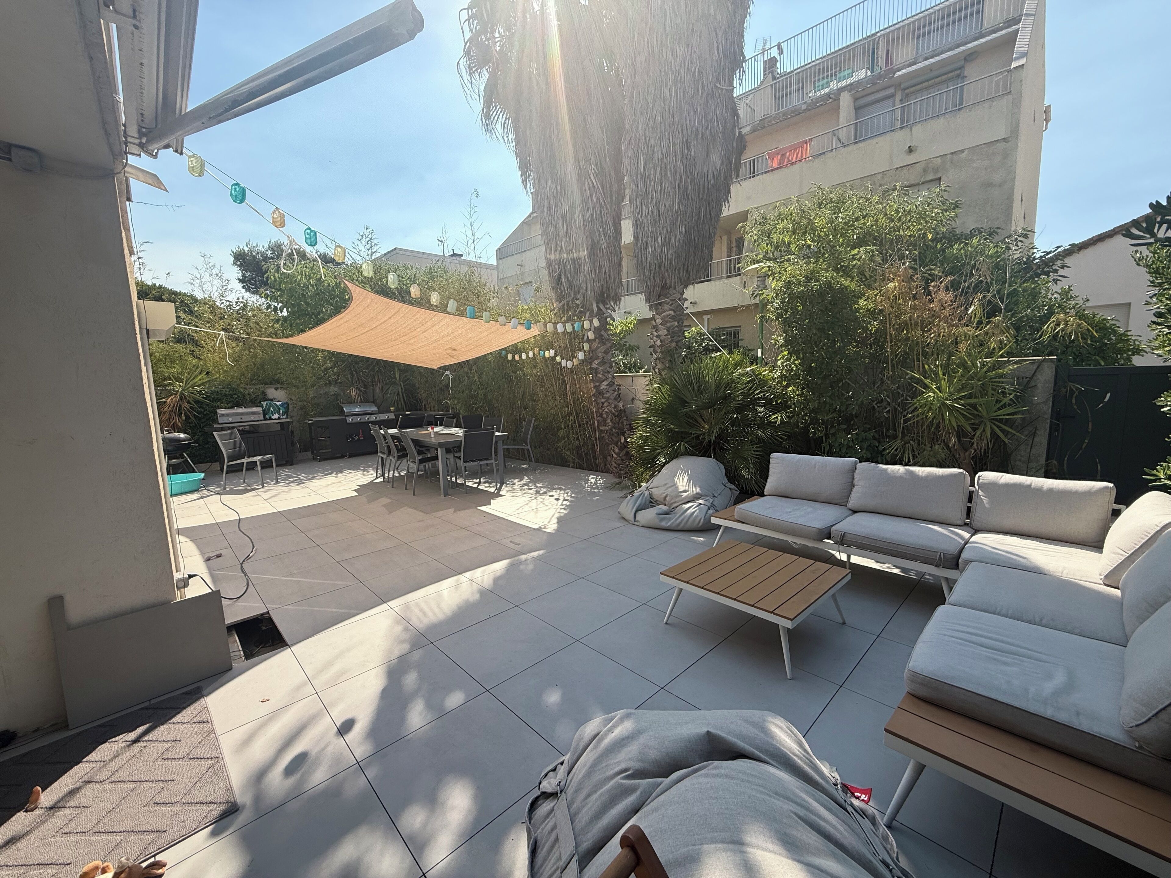 An outdoor patio with a grill, dining table, and seating area.