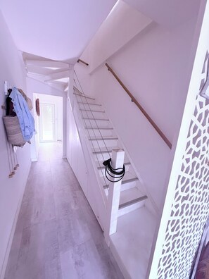 Ein schmaler Flur mit einer Treppe, die zu einer Tür am Ende führt.