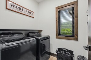 A laundry room with two washers and dryers, a sign above them, a window with blinds, and a door. - Lazy River, Pool, Theater, Arcade, Golf Sim, Views (Sevierville)