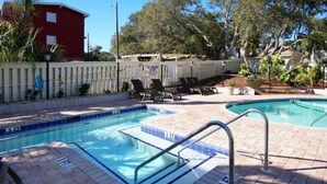 Ein Pool mit gefliestem Sonnendeck, Zaun und Liegestühlen.