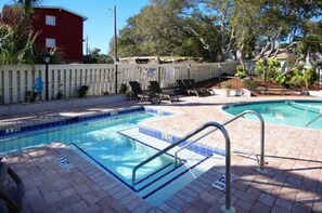 Ein Pool mit gefliestem Sonnendeck, Zaun und Liegestühlen.