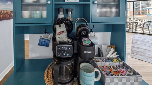Ein Kaffee-Bereich mit einer Keurig-Maschine, einer Kaffeemühle und einer Tasse.