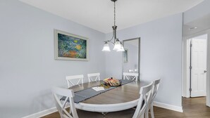 Ein Esszimmer mit einem runden Tisch, weißen Stühlen, einer Kristallleuchter und einem Gemälde an der Wand.