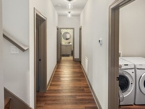 A hallway with wooden flooring, a mirror, a sink, and a washing machine. - 4BR cabin with hot tub, lake access, and excellent lake view (Bryson City)