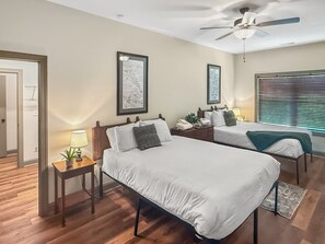 A hotel room with two beds, a ceiling fan, framed artwork on the walls, and a window with blinds. - 4BR cabin with hot tub, lake access, and excellent lake view (Bryson City)