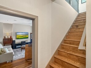 Eine Treppe führt zu einem Wohnzimmer mit an der Wand montiertem Flachbildfernseher.