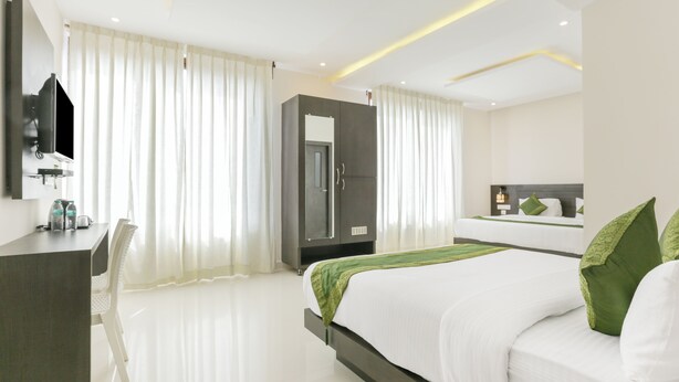 A modern hotel room with a bed, a desk, a wardrobe, and a television. - Hotel Sunrise Luxury Stays (Chikkamagaluru)