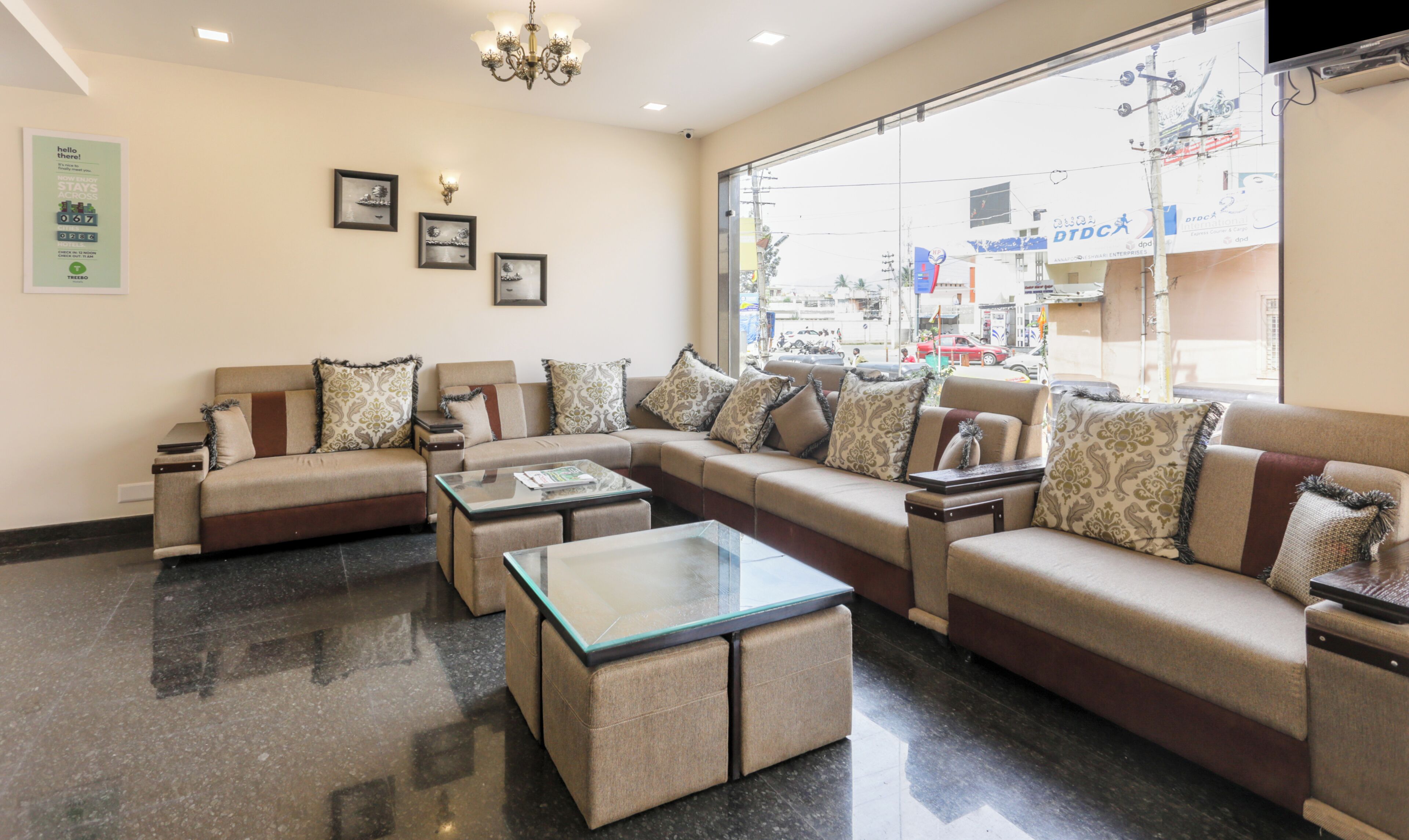 A modern living room with a sectional sofa, a glass coffee table, and a chandelier.