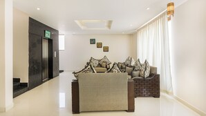 A hotel lobby with a reception desk, a seating area with patterned cushions, and a staircase. - Hotel Sunrise Luxury Stays (Chikkamagaluru)