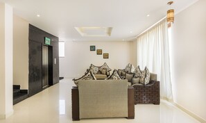A hotel lobby with a reception desk, a seating area with patterned cushions, and a staircase. - Hotel Sunrise Luxury Stays (Chikkamagaluru)